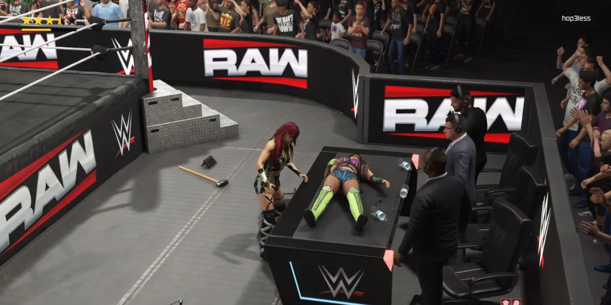 Io Sky chuẩn bị thực hiện đòn tấn công lên Dakota Kai đang nằm trên bàn bình luận viên trong WWE 2K25
