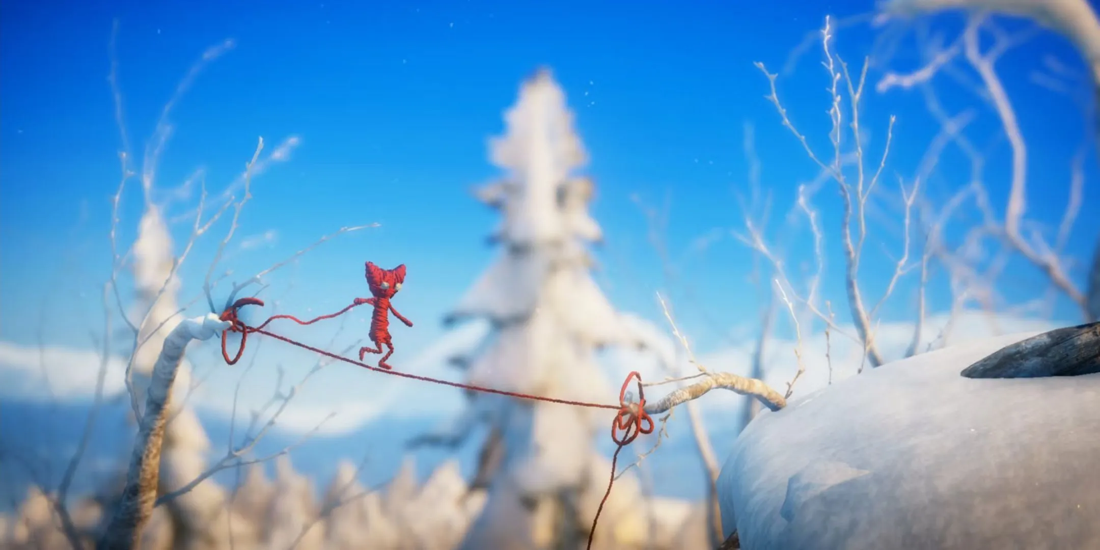 Nhân vật Yarny bằng len đỏ đang đi trên một sợi dây len trong game Unravel.